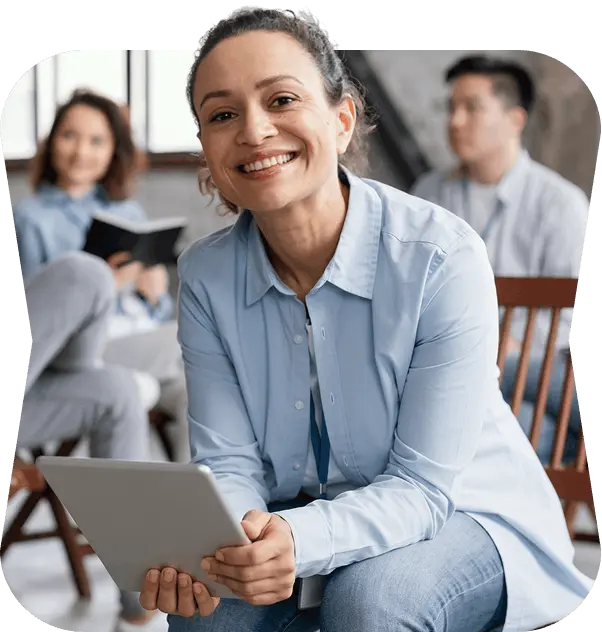 Smiling life coach holding a tablet during a group session